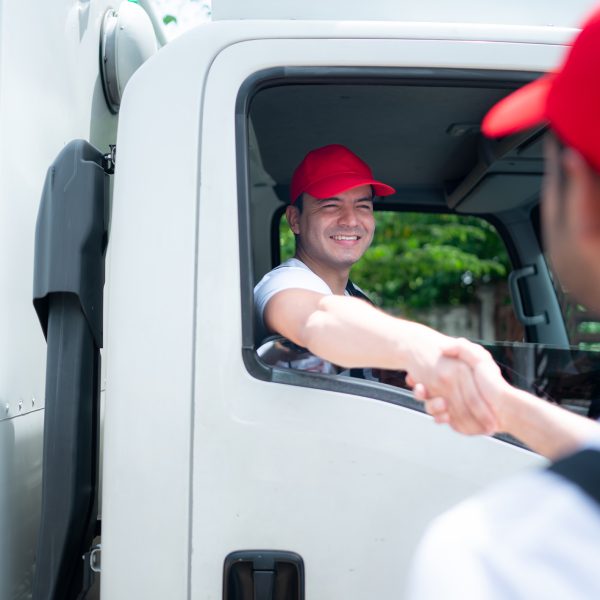 Delivery man in red cap and uniform handshaking each other after finishing deliveries.